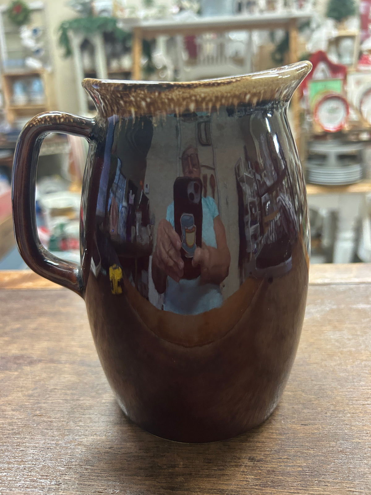 Brown ceramic drip-glaze pitcher with glossy surface, curved handle, and spout.
