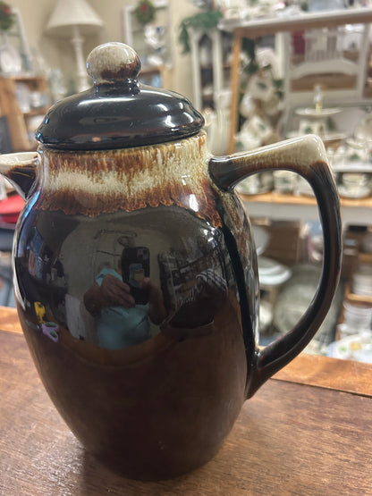 Brown ceramic drip coffee pot with dark teal lid, curved spout, side handle