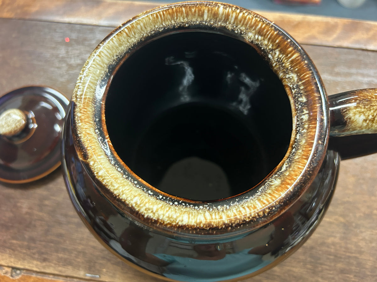 Open brown bean pot with gold drip rim, dark interior, curved side handle.
