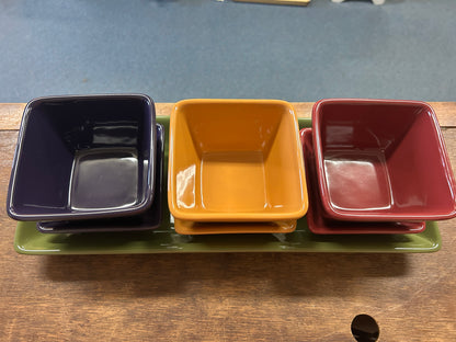 Three square dishes on green tray: navy, orange, and red with glossy finish