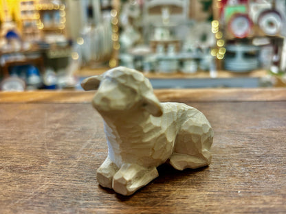 Cream sheep nativity figurine lying on wooden tabletop