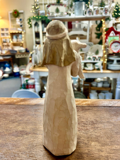 Cream nativity girl figurine, back view standing on wooden tabletop