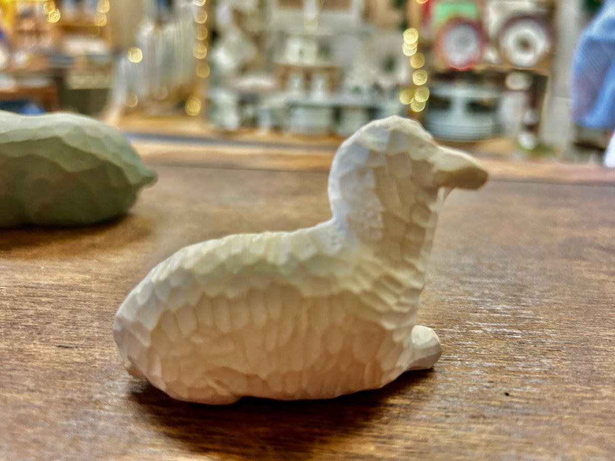 Cream sheep nativity figurine lying on wooden tabletop