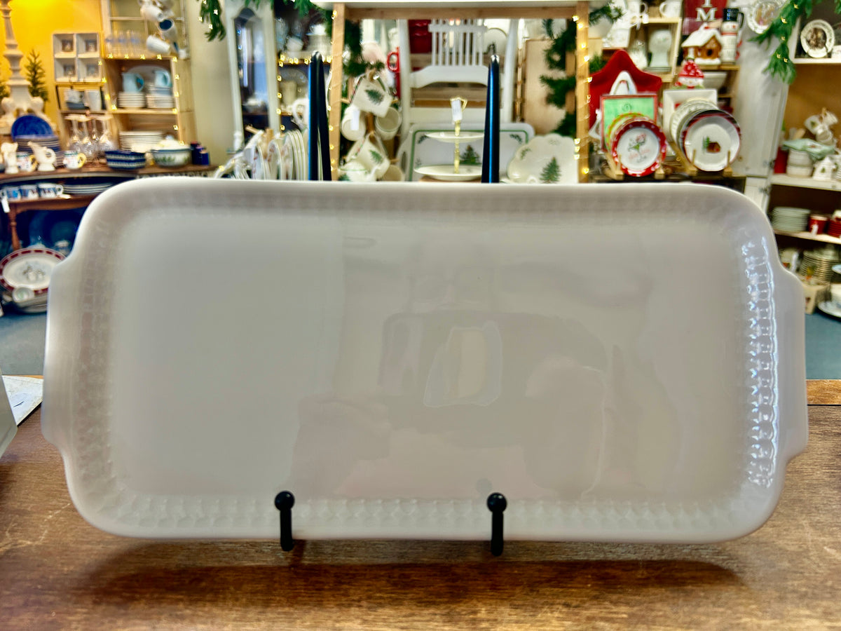 White rectangular ceramic platter with raised rim, on display stand