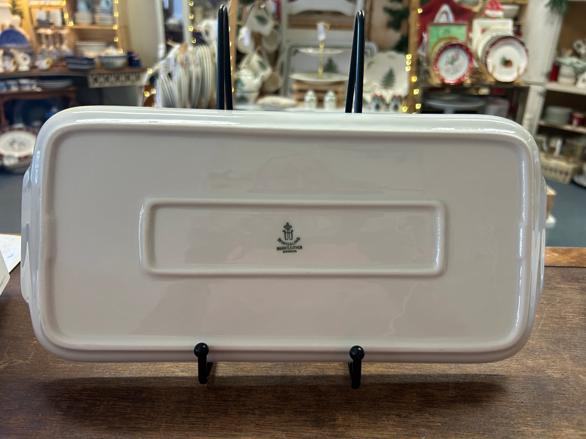 White rectangular ceramic platter with embossed emblem panel, on display stand