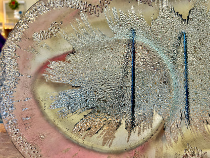 Silver round divided platter close-up with speckled splash texture and central divider