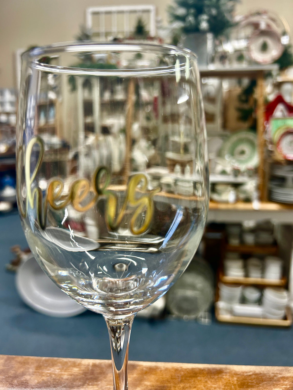 Clear stemmed wine glass with gold “Cheers” design on the front