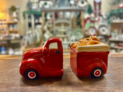 Small red ceramic truck figurine with white stripes and black wheels, side view.
