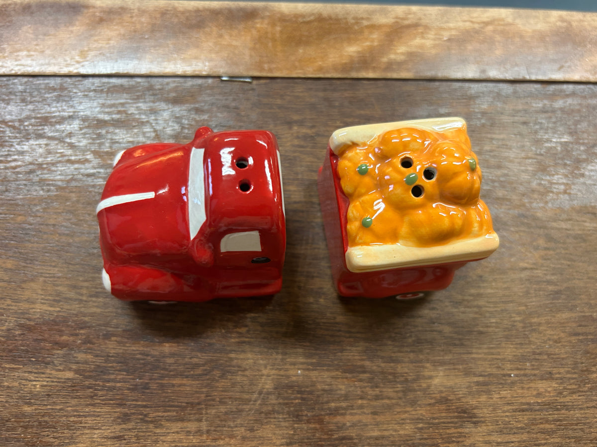 Red ceramic truck and orange ceramic pumpkin figurine with face details, front view.