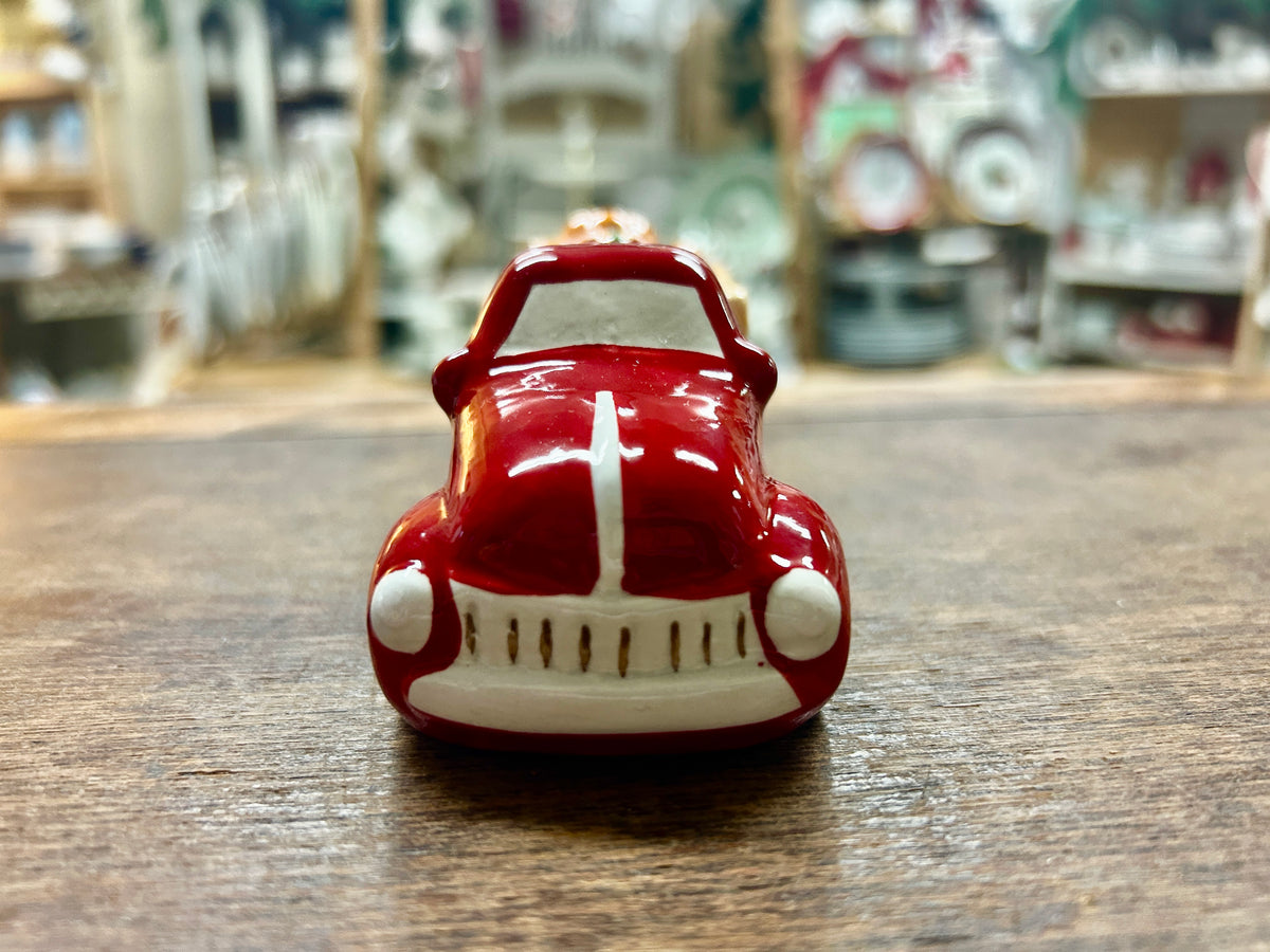 Red ceramic truck figurine with white bumper and grille lines, front view.