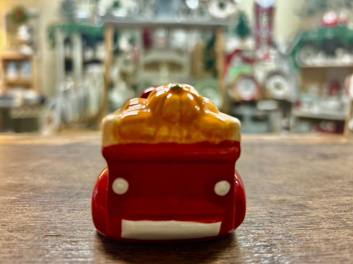 Orange and red ceramic truck figurine with white wheels, rear view.
