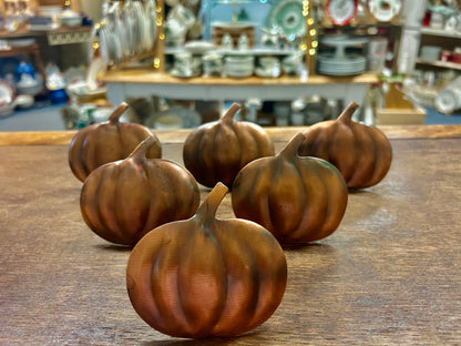 Set of copper pumpkin-shaped napkin rings, clustered on a tabletop