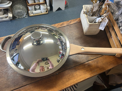 Covered skillet with stainless lid and wooden handle, close-up