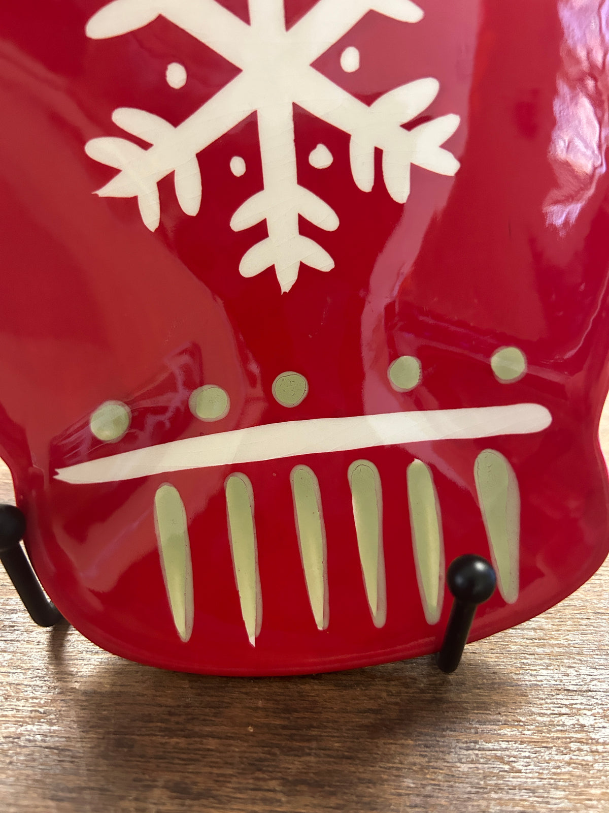 Close-up of red mitten plate showing white snowflake, comb stripes, and green dots