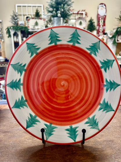 Christmas decorative plate with orange spiral center, green pine tree border, red rim