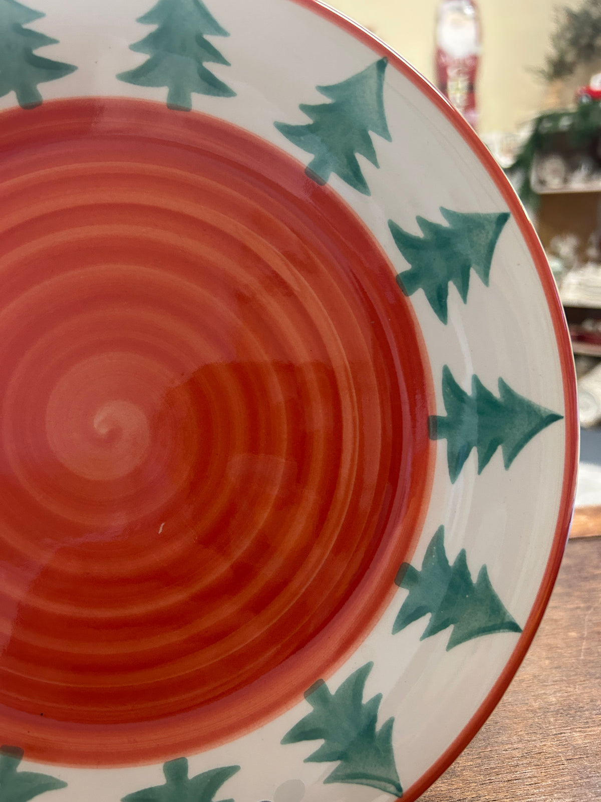 Orange spiral interior Christmas plate with green pine tree motif and red rim