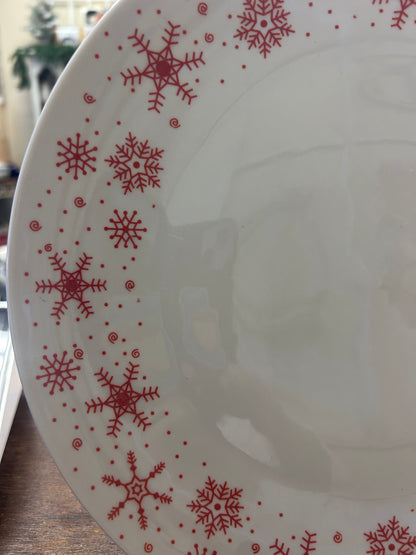 White plate with scattered red snowflakes and dot accents along rim