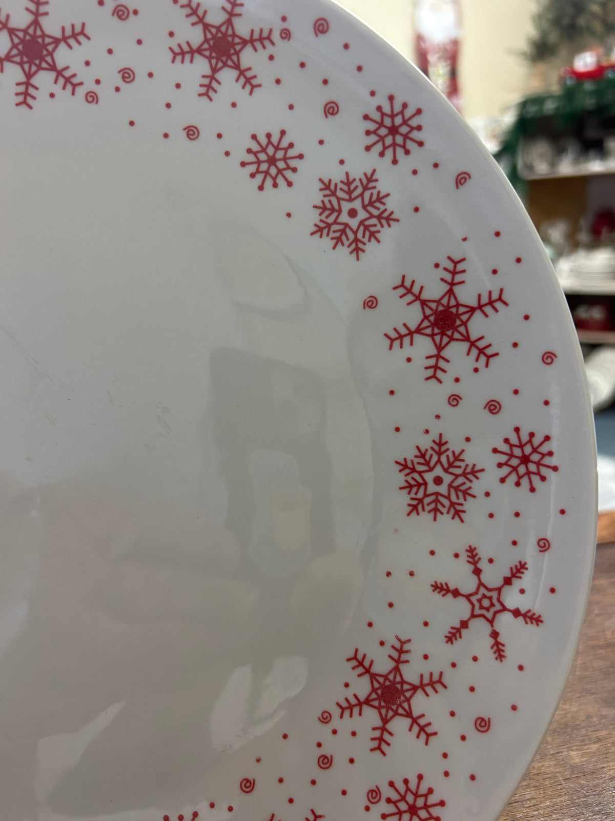 White round plate with red snowflakes and small red dots, close side view