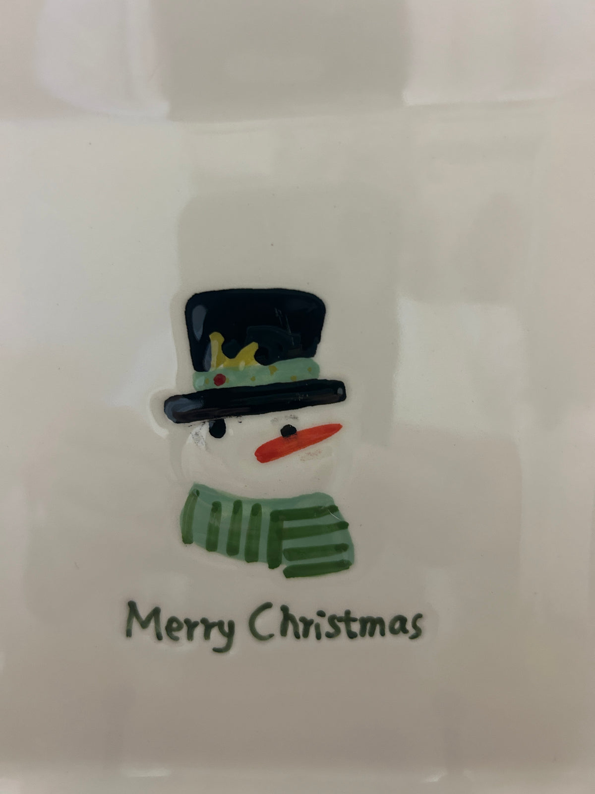 White square Christmas plate close-up of snowman cut-out and “Merry Christmas”