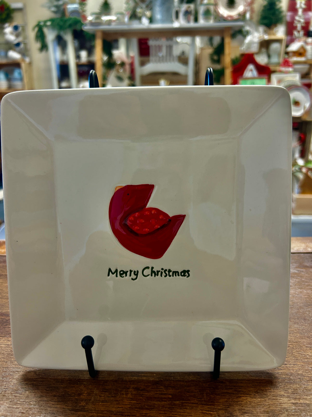 Square decorative plate with red cut-out bird and “Merry Christmas” text on white