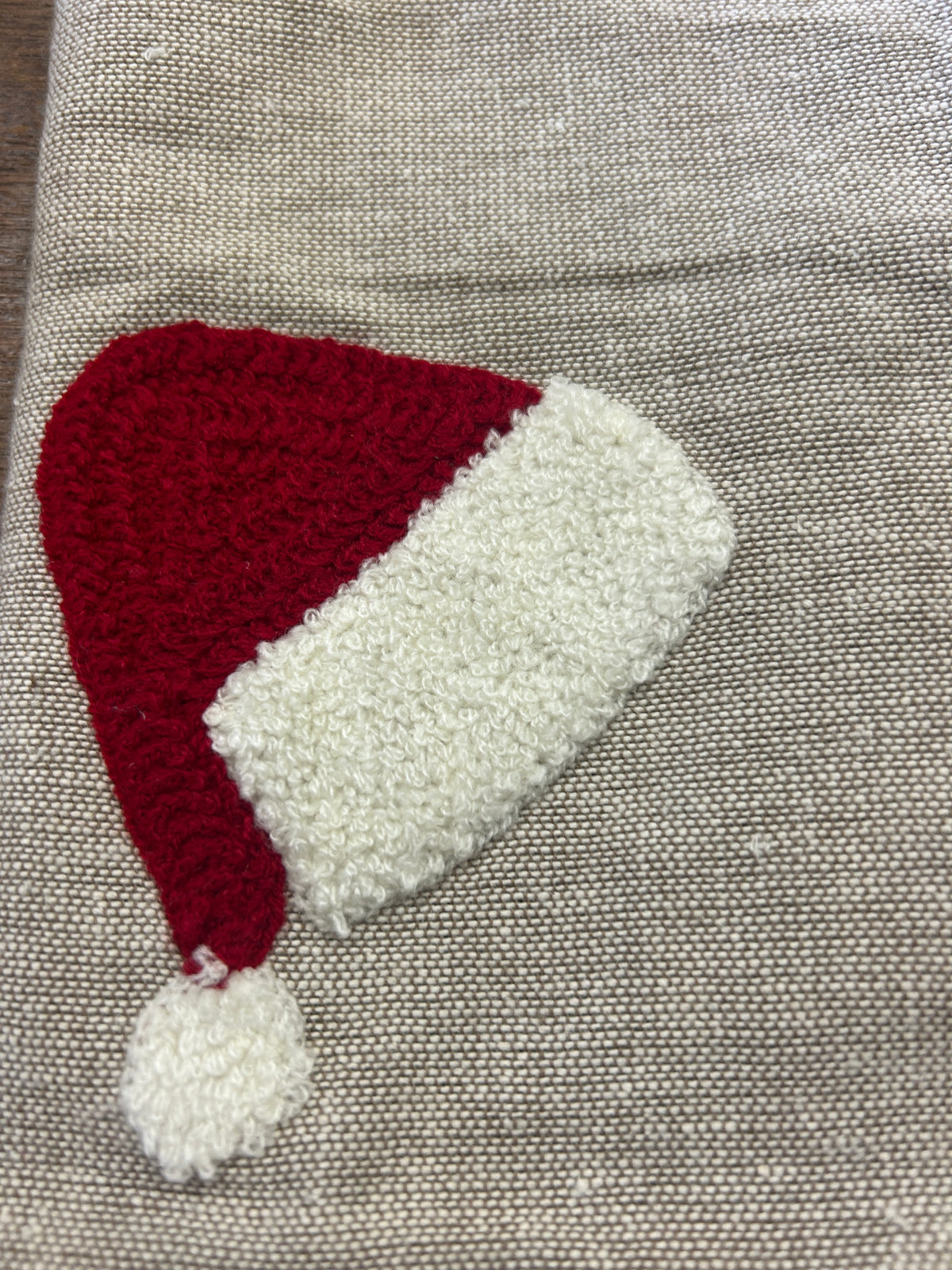 Linen-style napkin with red Santa hat applique and white fuzzy brim, close-up