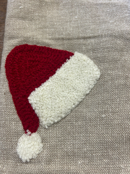 Linen-style napkin with red Santa hat applique and white fuzzy brim, close-up