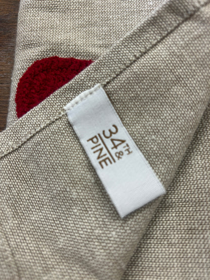 Linen-style napkin label on folded edge with red Santa hat applique