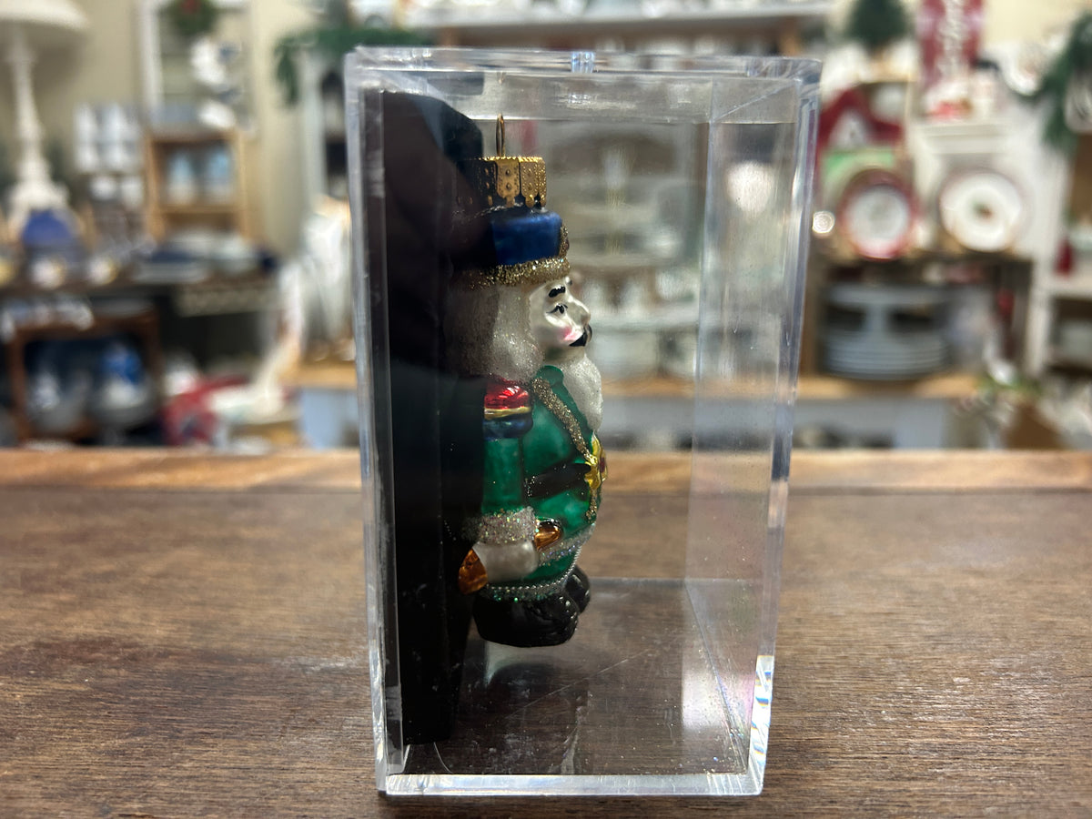 Nutcracker ornament in clear box, side view of blue hat soldier in green coat