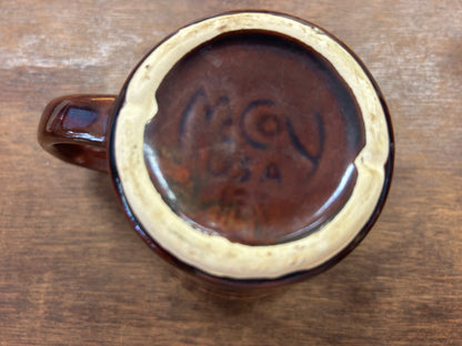 Bottom view of brown ceramic mug with speckled outer ring and molded mark
