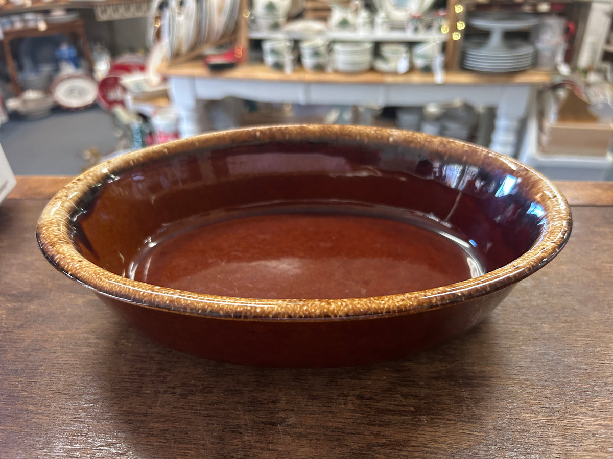Oval brown glazed baking dish with speckled gold-toned drip rim