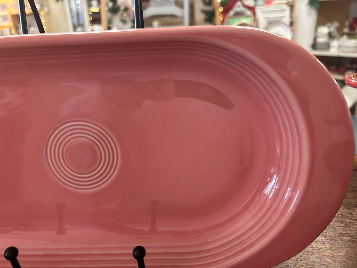 Pink oval ceramic platter with concentric circle emblem and glossy glaze