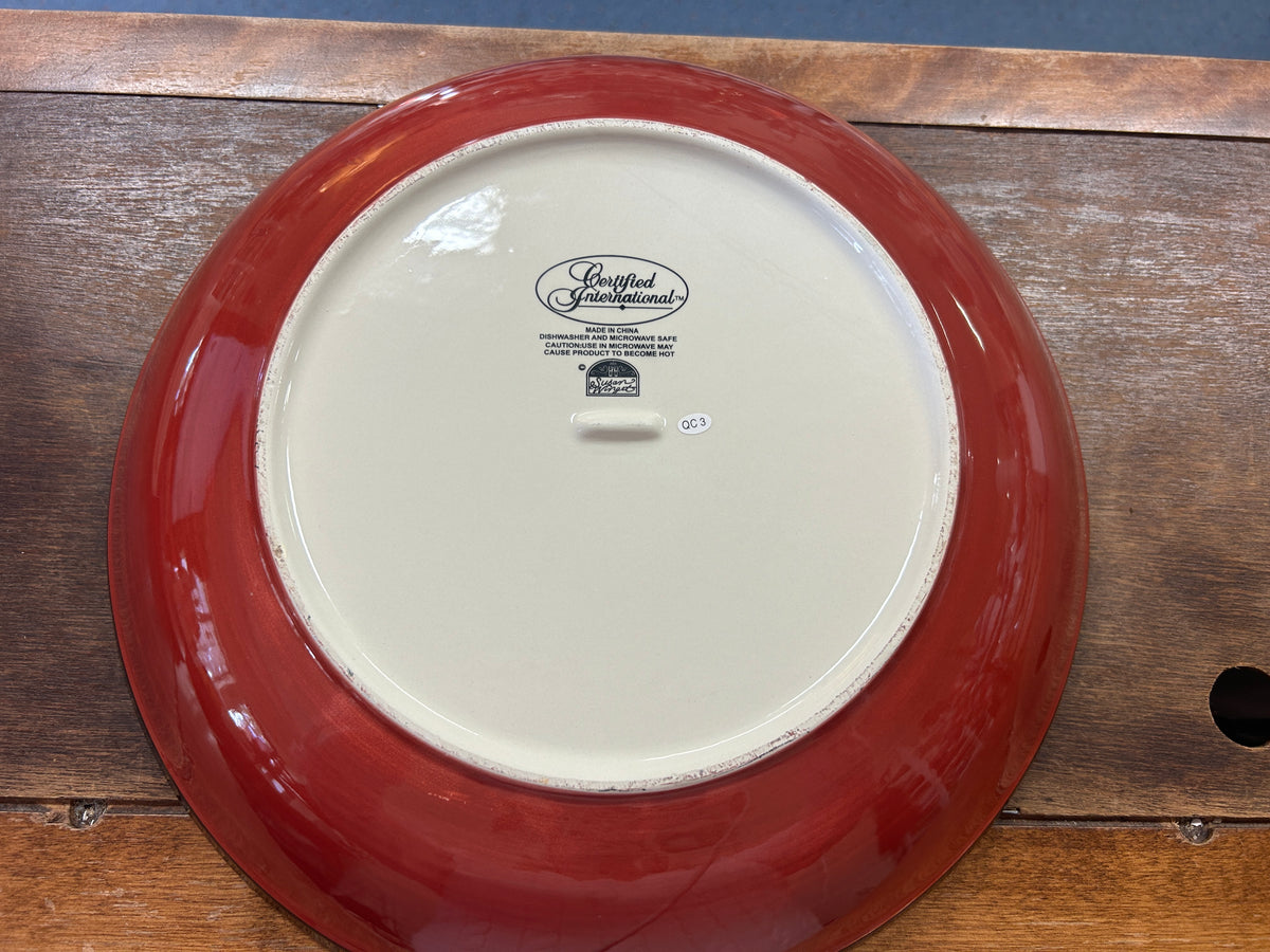 Red ceramic bowl underside with white center and small maker stamp